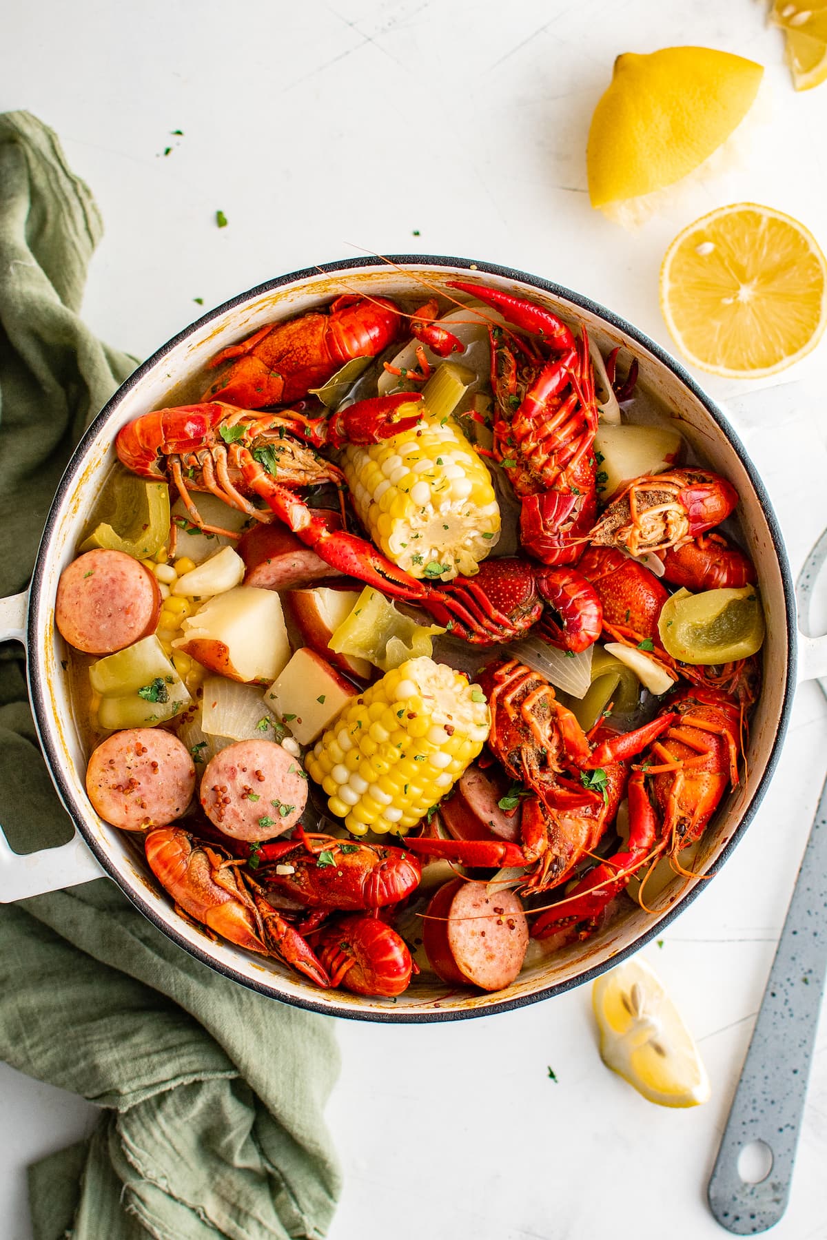 A pot of crawfish boil with lemon wedges and a tea towel.