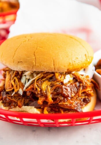 A sandwich with shredded bbq chicken in a red basket.