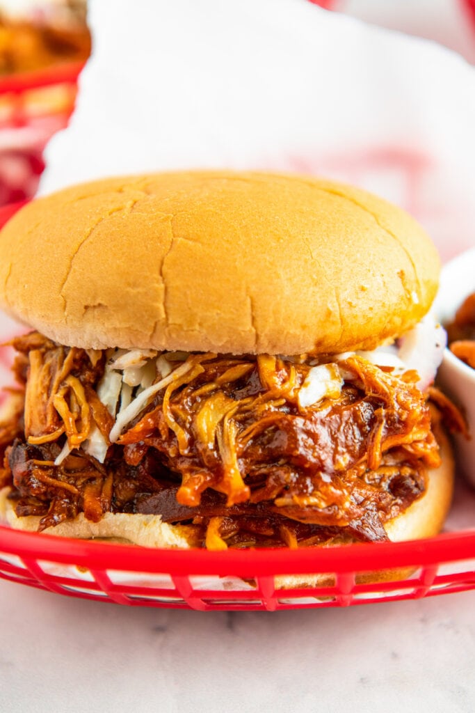 A sandwich with shredded bbq chicken in a red basket.