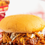 A chicken bbq sandwich with slaw in a red basket.