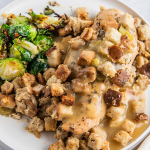 a plate of crockpot chicken and stuffing with a side of brussels sprouts
