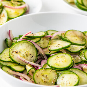 A bowl of cucumber salad with red onions.