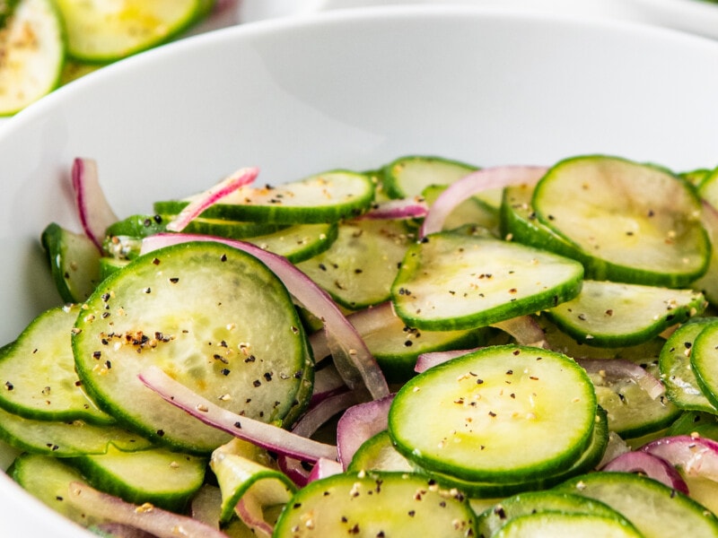 A bowl of cucumber salad with red onions.