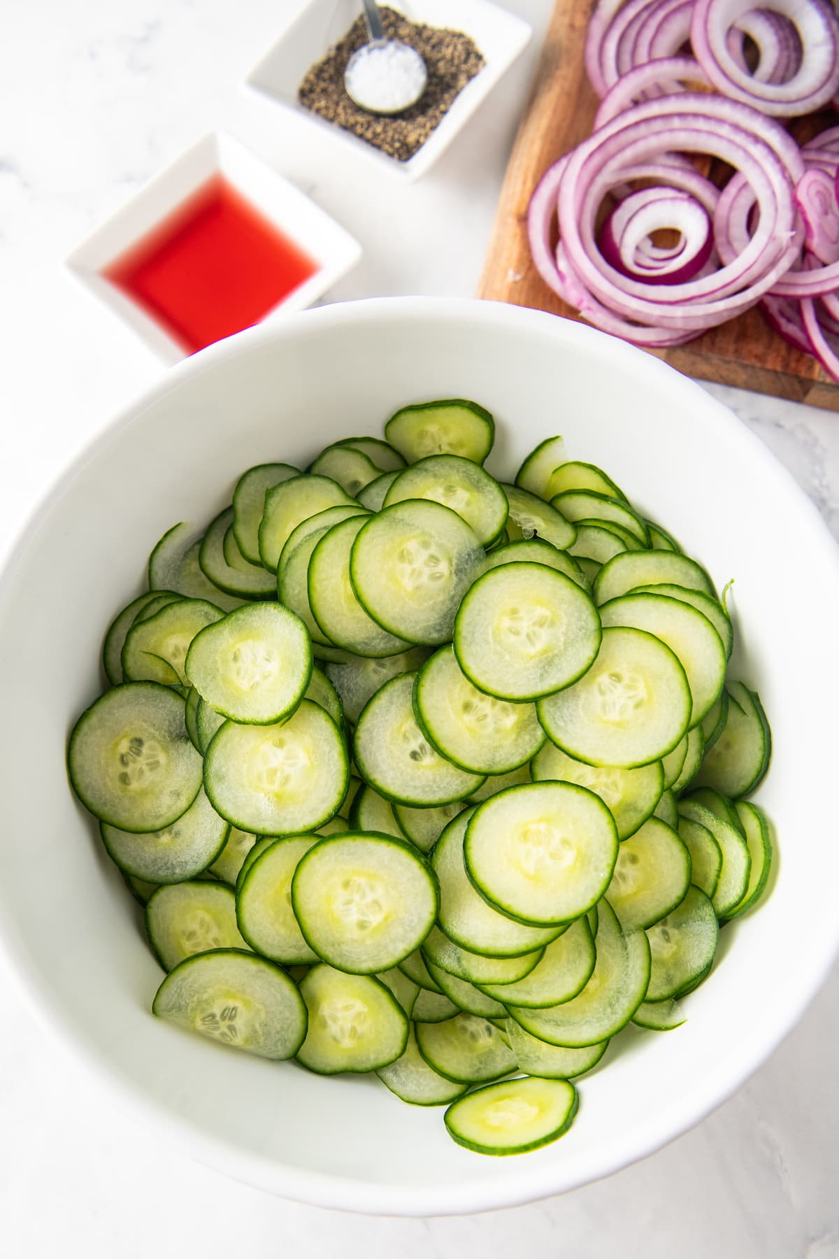 Sliced cucumbers in a white bowl.