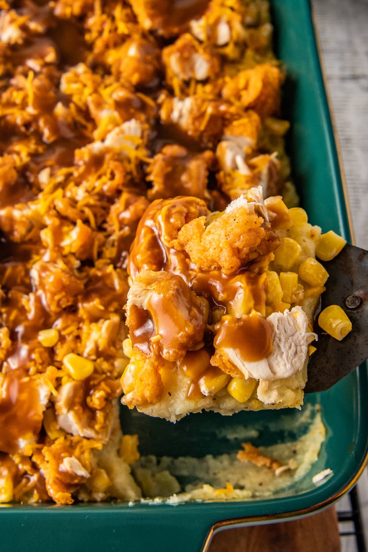 close up of a slice of fried chicken casserole with mashed potatoes, corn, cheese, and gravy