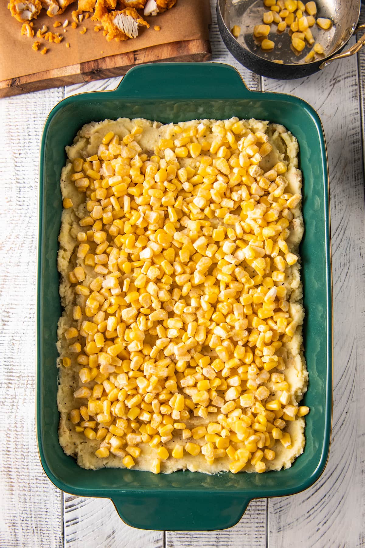 corn sprinkled on top of mashed potatoes in a baking dish