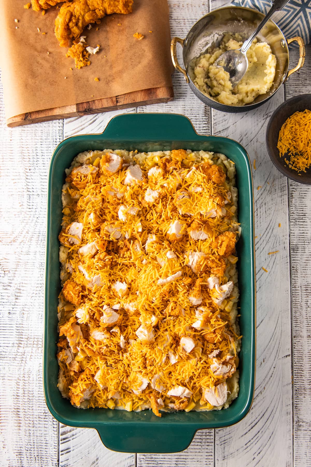 a casserole dish with fried chicken and shredded cheese on top