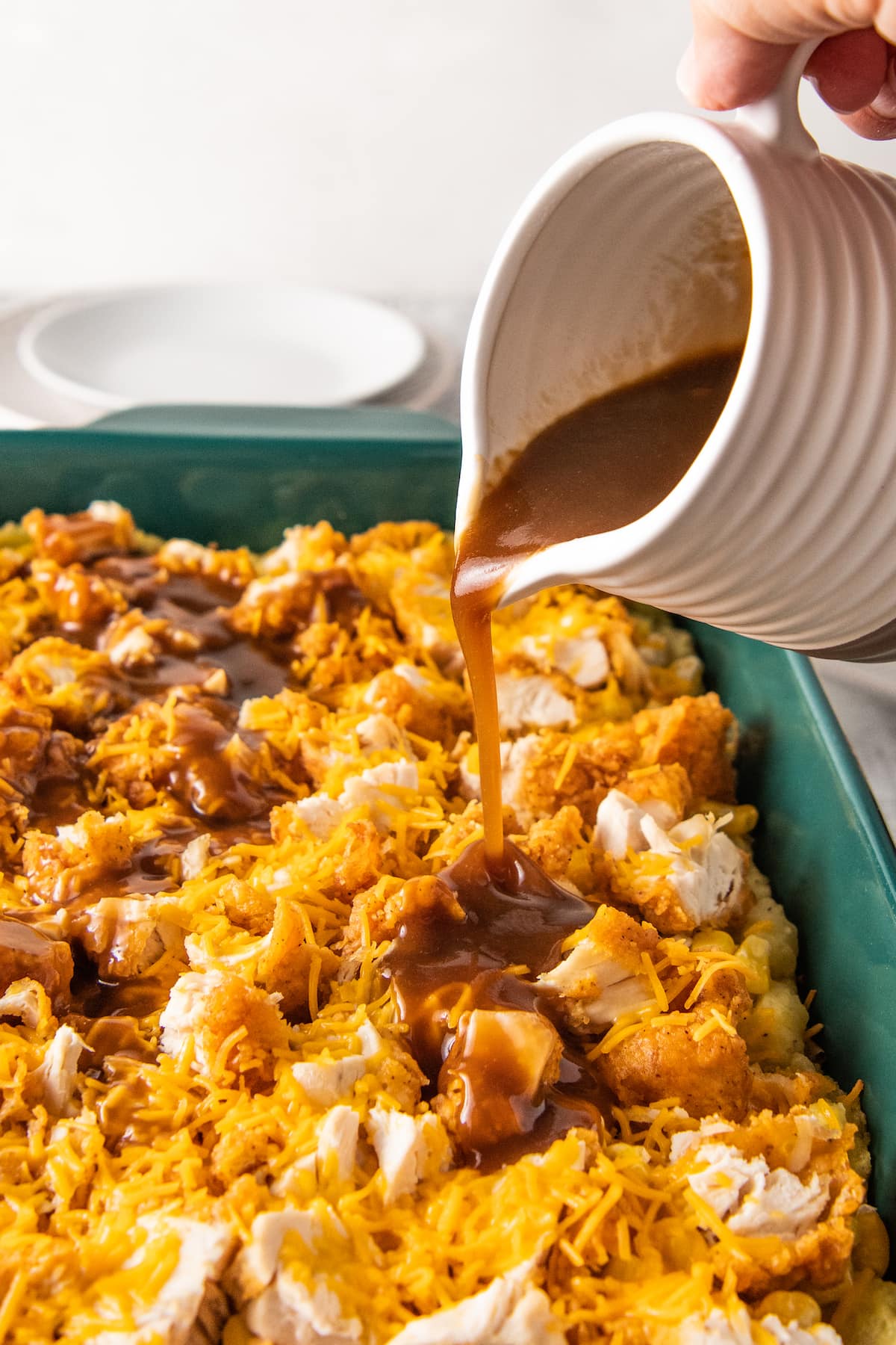 pouring brown gravy into a chicken casserole dish