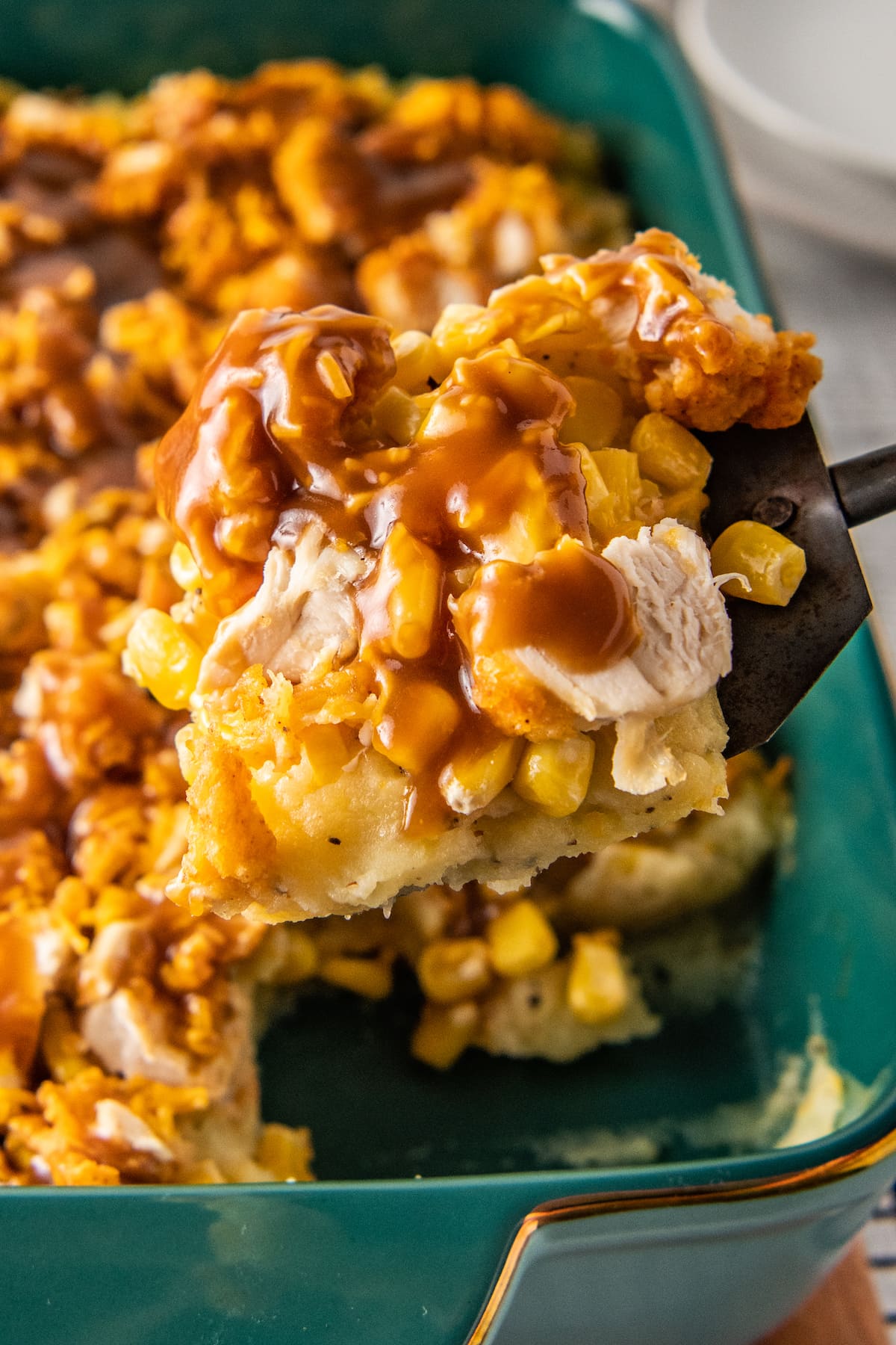 close up of a slice of fried chicken casserole with mashed potatoes, corn, cheese, and gravy