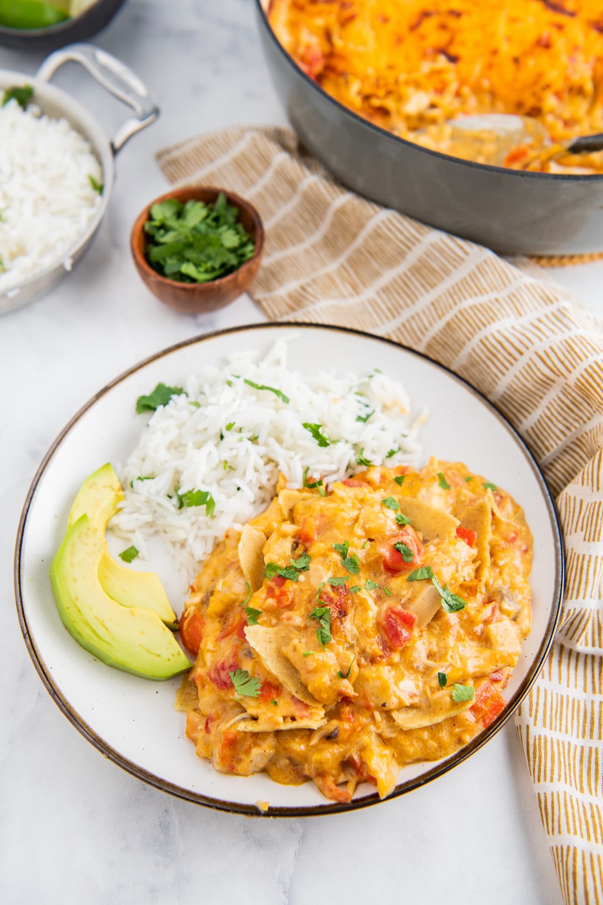 a plate with chicken and cheese casserole with sliced avocado and rice