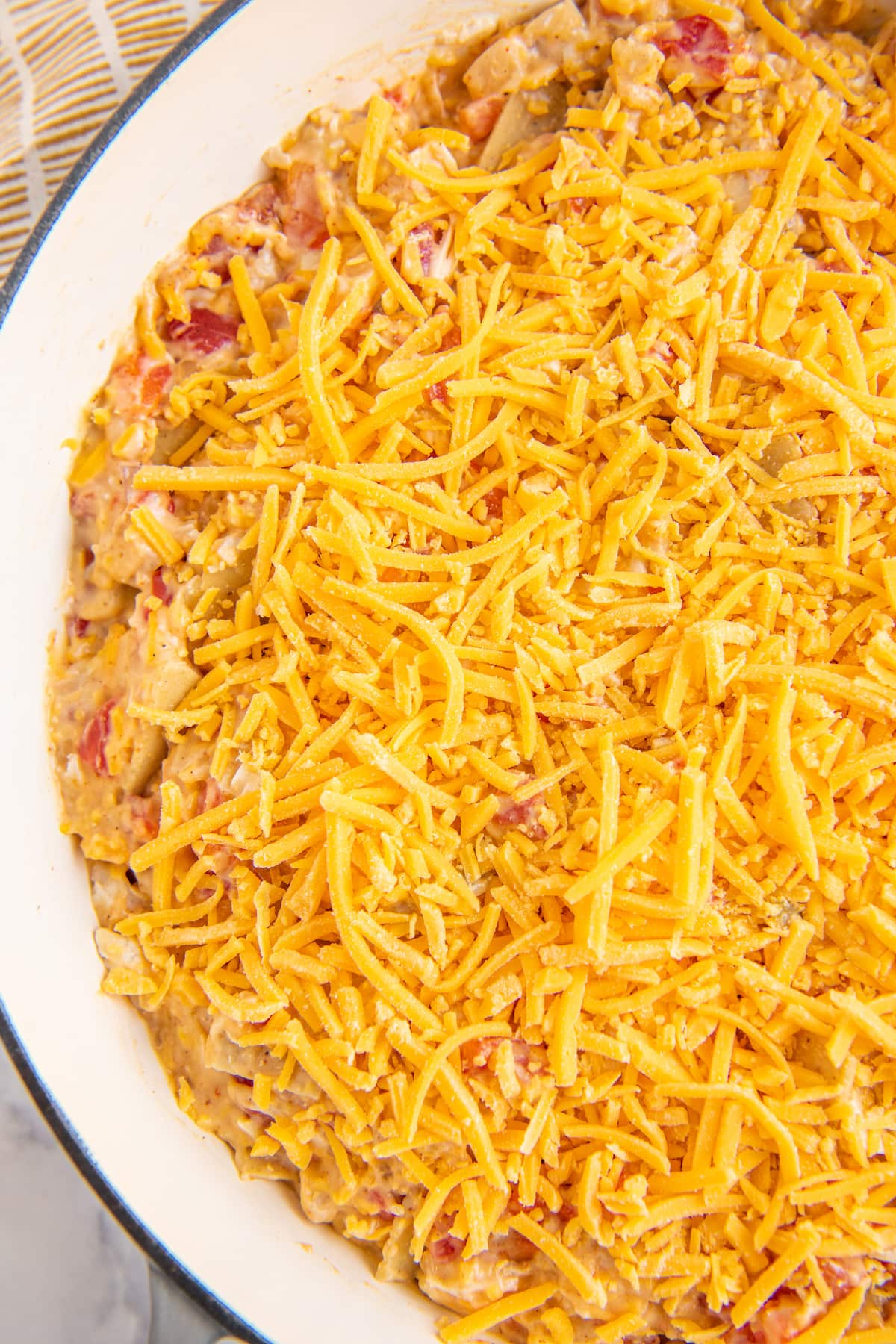a platter with a chicken casserole and shredded cheese on top