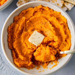 a bowl of mashed sweet potatoes with a pad of butter in the middle