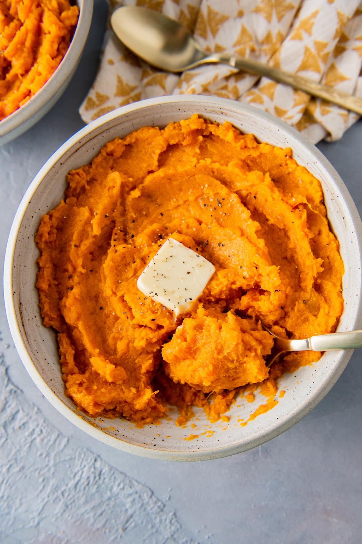 a bowl of mashed sweet potatoes with a pad of butter in the middle