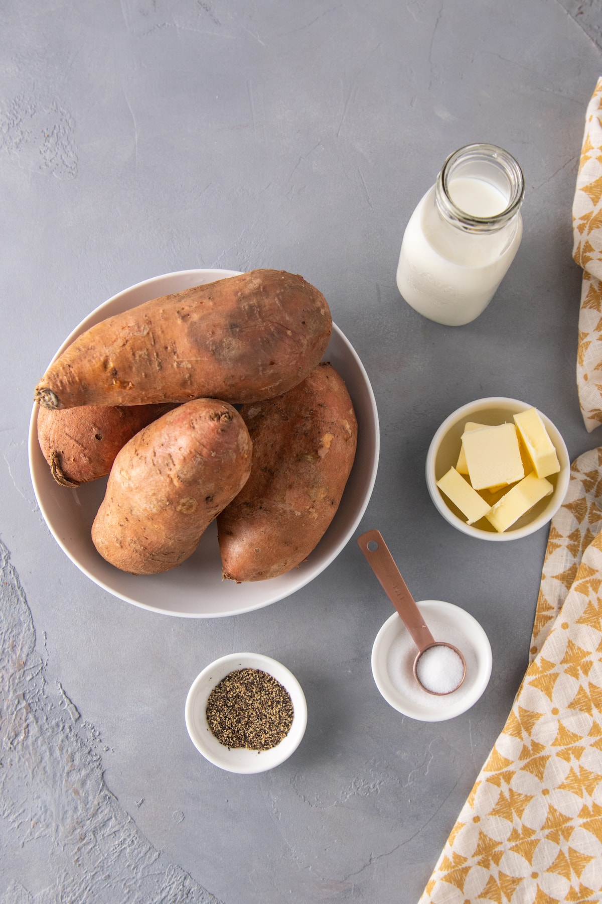 seperate bowls of sweet potatoes, butter, cream, salt, and pepper