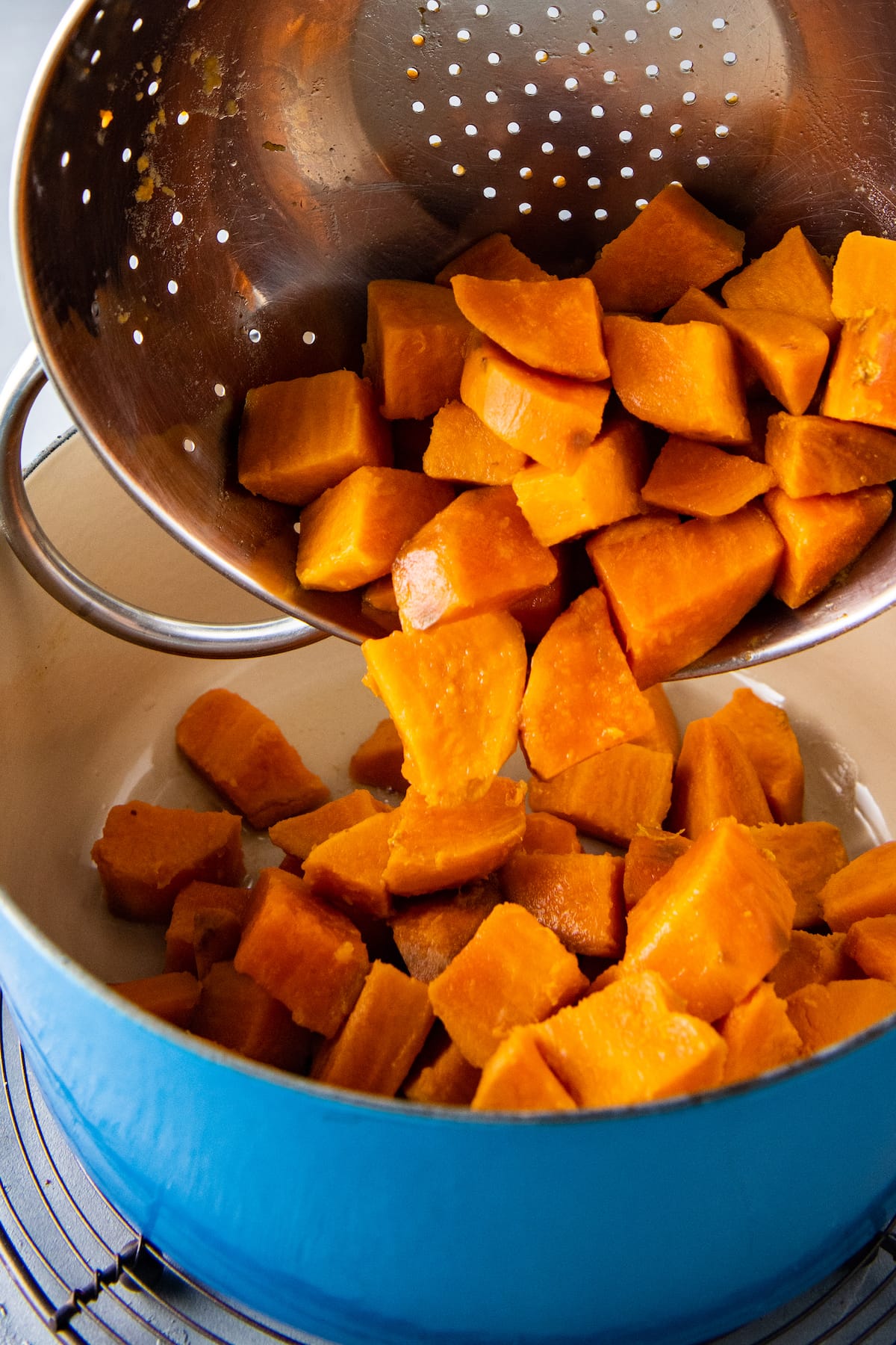 returning cubed sweet potatoes to a pot from a strainer