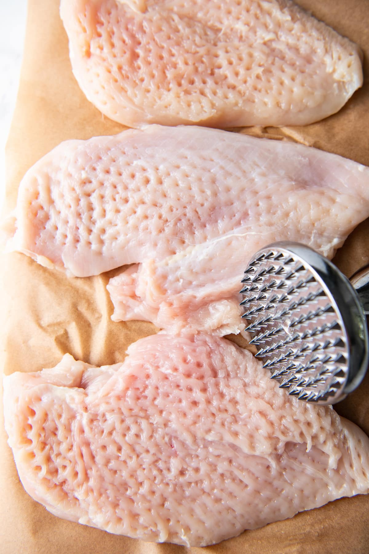 raw chicken that has been pounded with a meat mallet