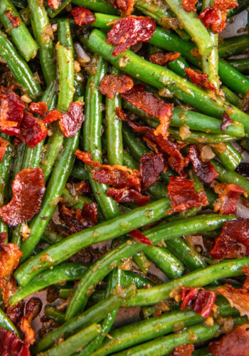 Sautéed green beans with bacon in a skillet.