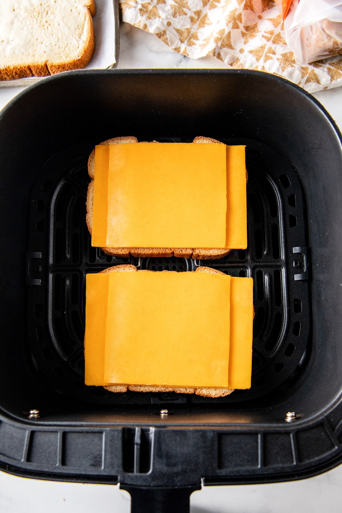 sliced cheese on sandwich bread in an air fryer