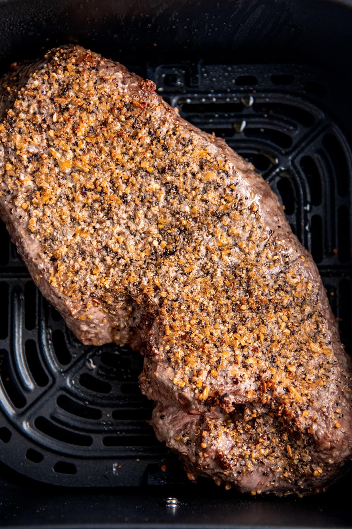 Cooked and seasoned steak in an air fryer tray