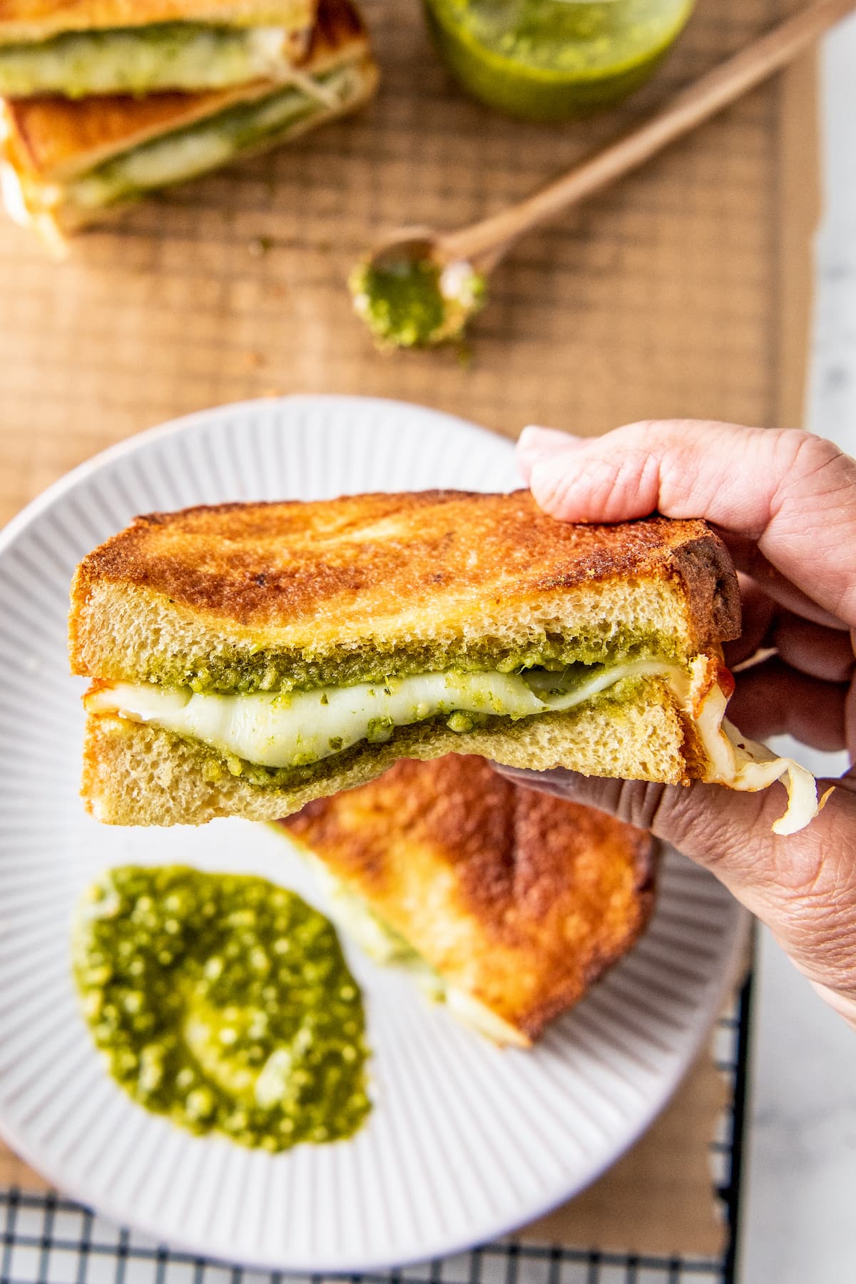 a hand showing the inside of a pesto grilled cheese sandwich