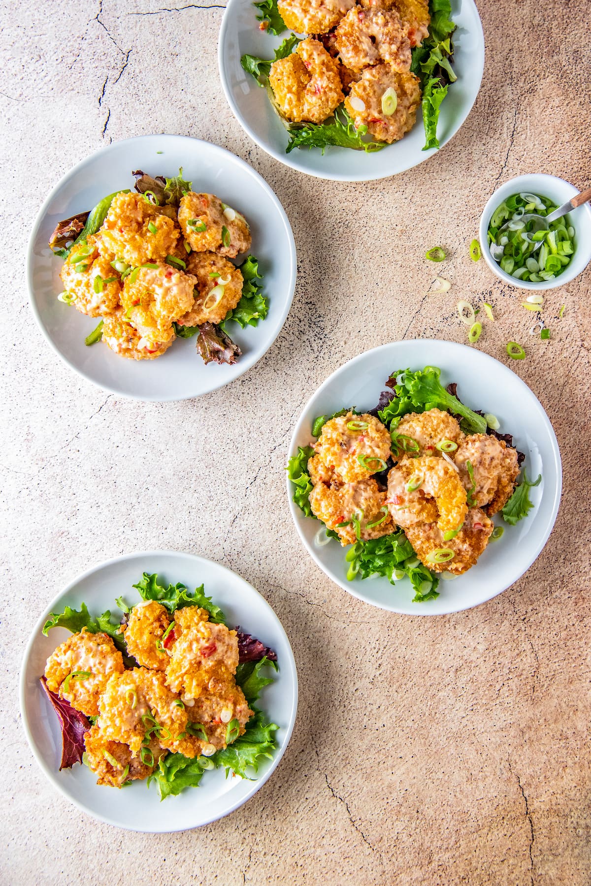 three plates with fried shrimp and sauce on top o a bed of lettuce