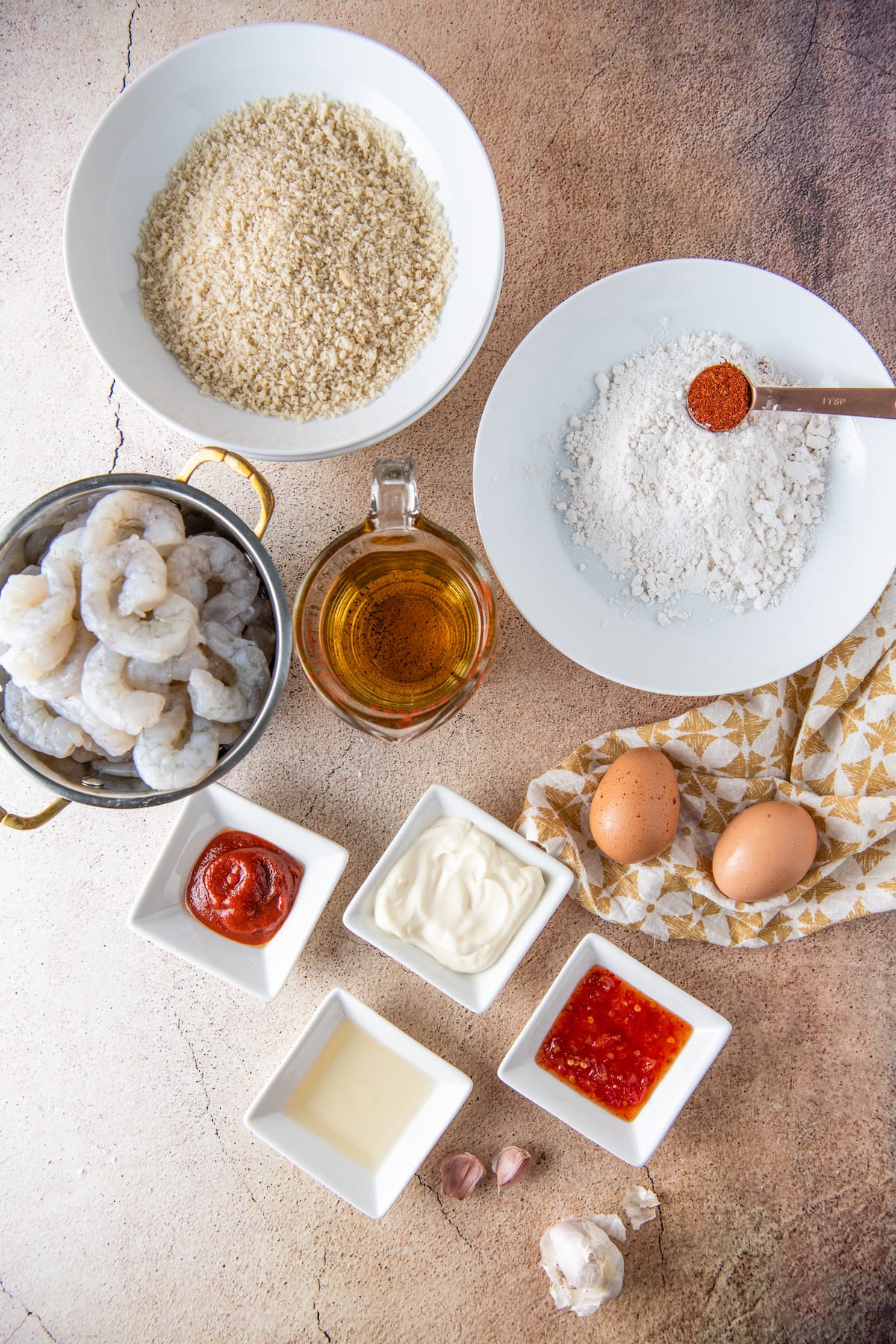 countertop with individual bowls of shrimp, panko bread crumbs, eggs, and other seasonings.