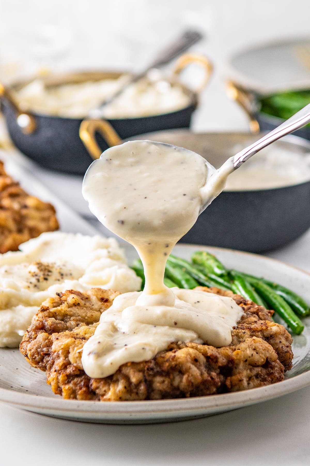 pouring white gravy onto chicken fried steak