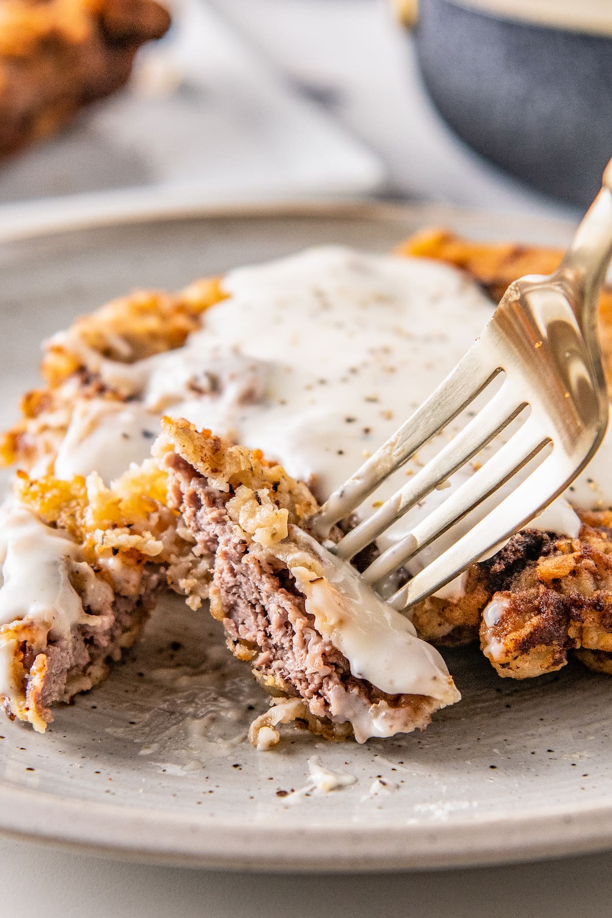 chicken fried steak with white gravy on top and a fork taking a bite off