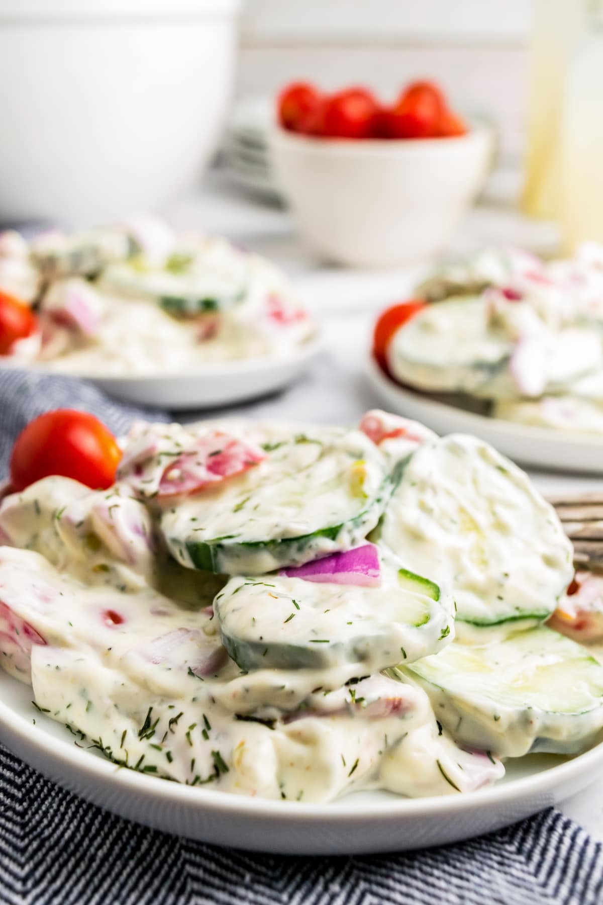 close up of creamy cucumber saald with red onions and tomato garnish