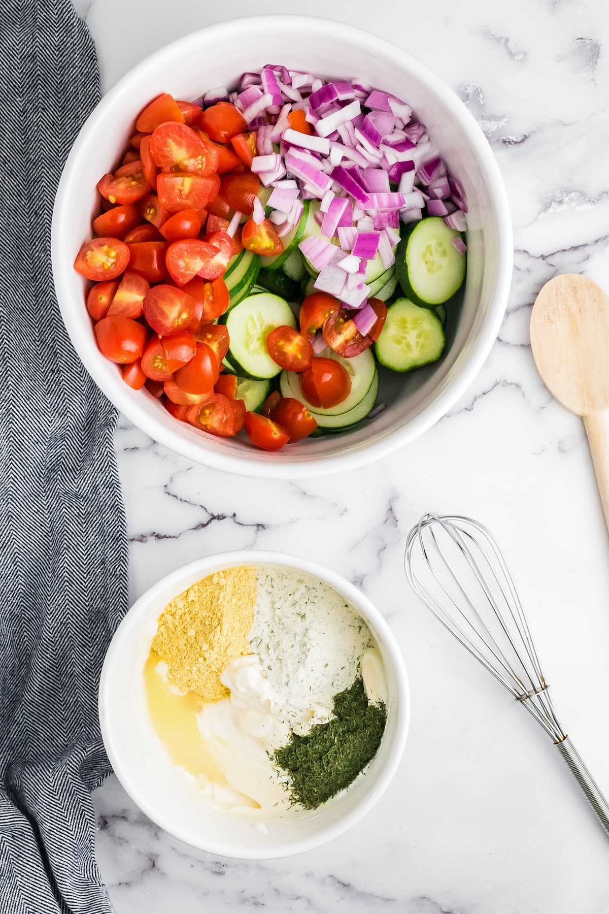 a bowl of fresh salad vegetables alongside another bowl with creamy dressing ingredients