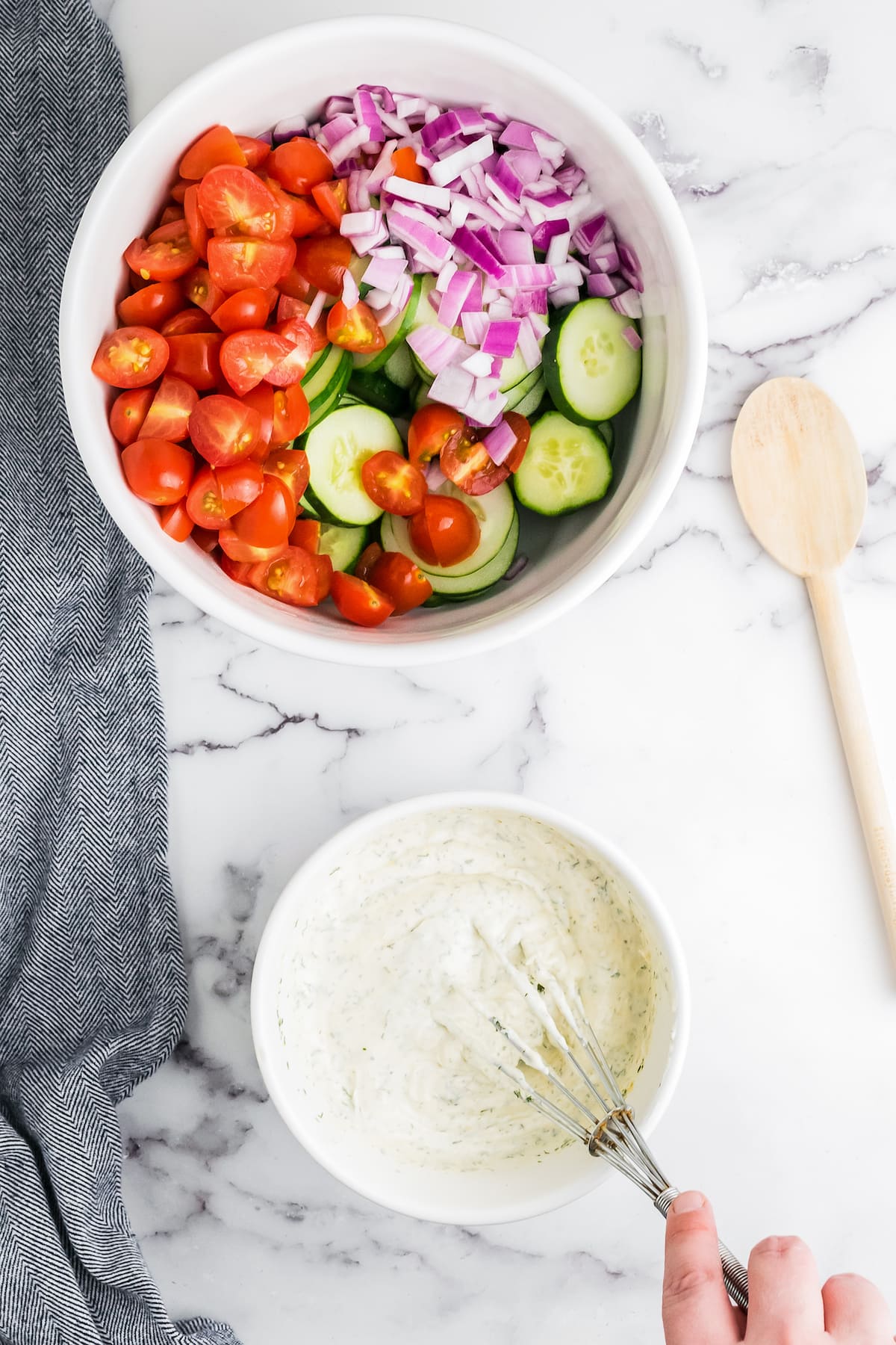 a bowl of fresh salad vegetables alongside another bowl with creamy dressing