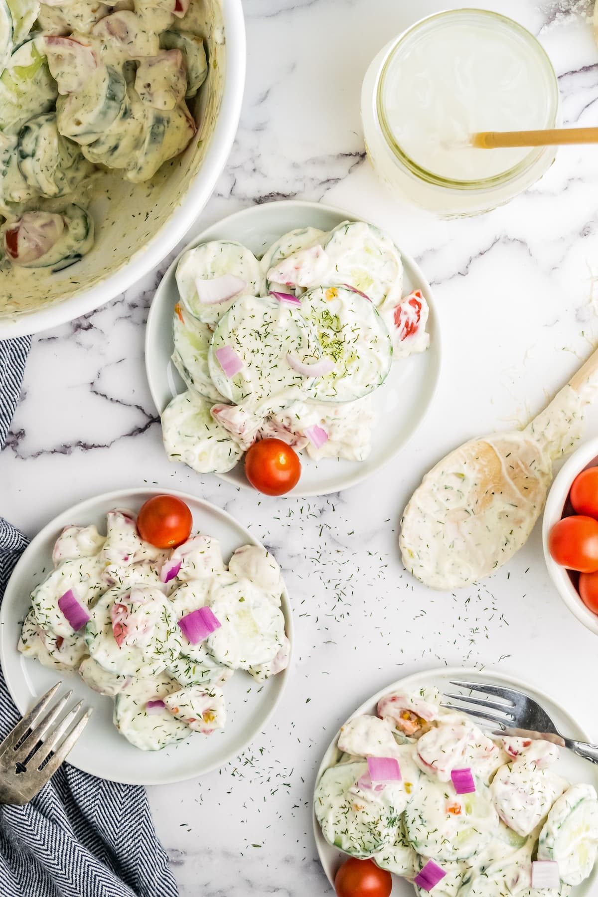 three plates with a creamy cucumber salad and cherry tomato for garnish