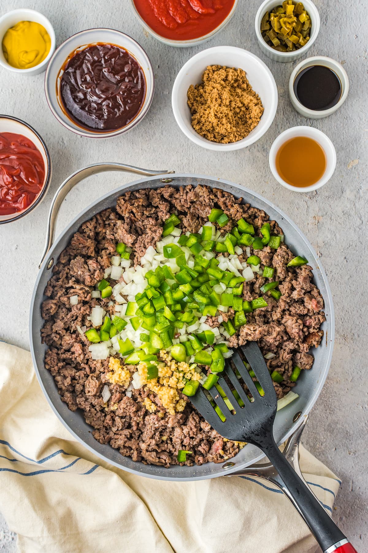 a casserole dish with cooked ground beef and chopped onions and green peppers on top