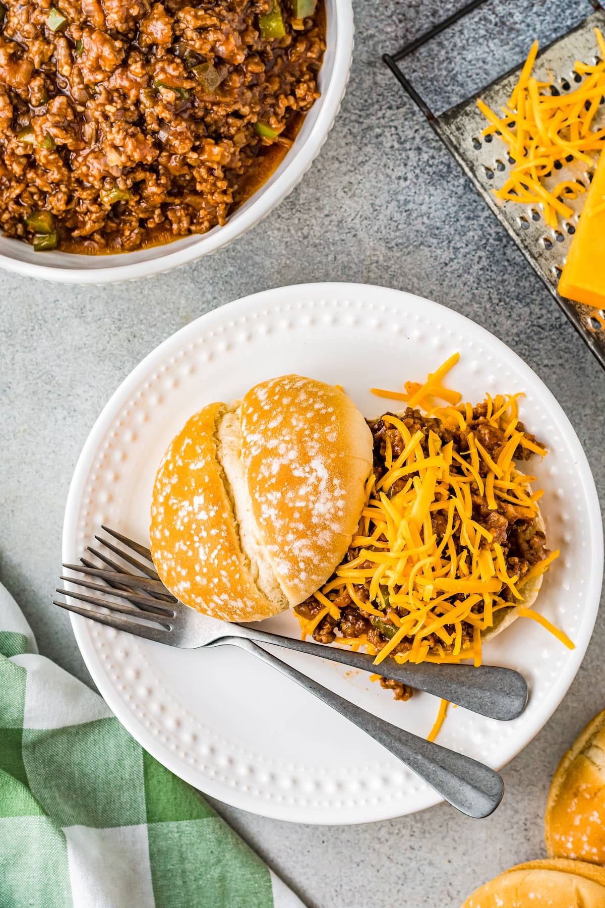 Sloppy Joe sandwich with beef, meat sauce, and shredded cheese on a plate with a fork