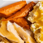 up close image of turkey, mashed potatoes, carrots and gravy on top.
