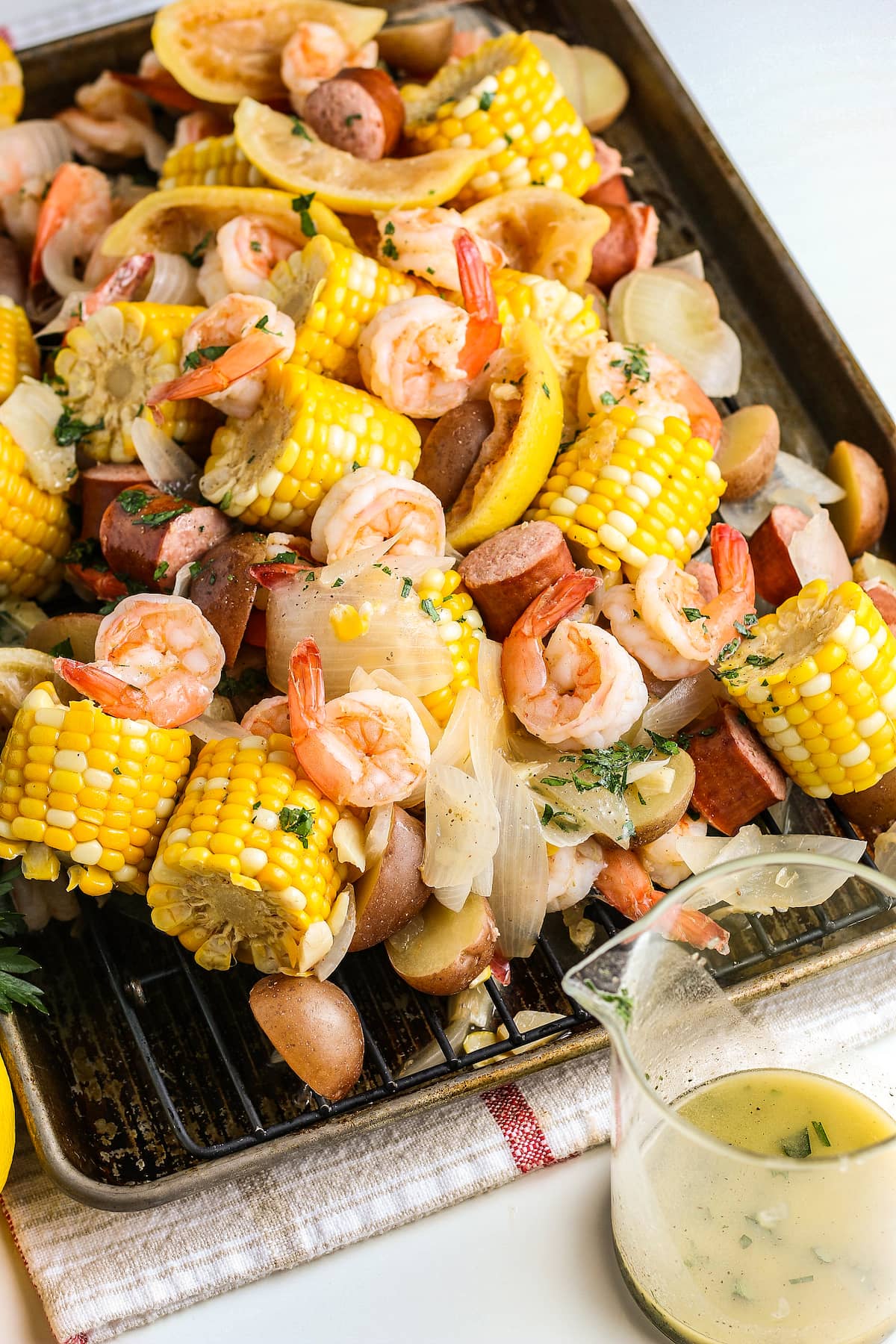 shrimp boil with shrimp, sausage, corn on the cob, lemons, and potatoes and a side of melted butter