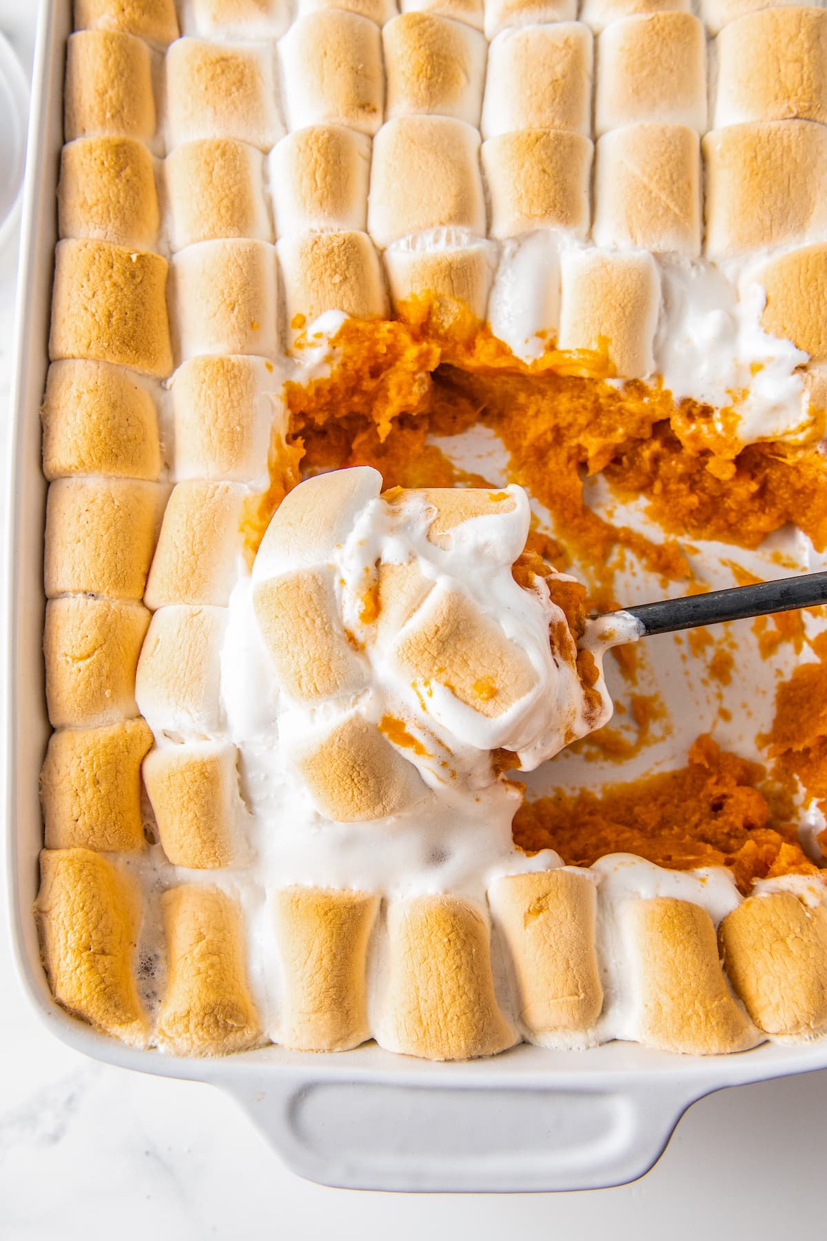 sweet potato casserole with a serving spoon taking a portion out