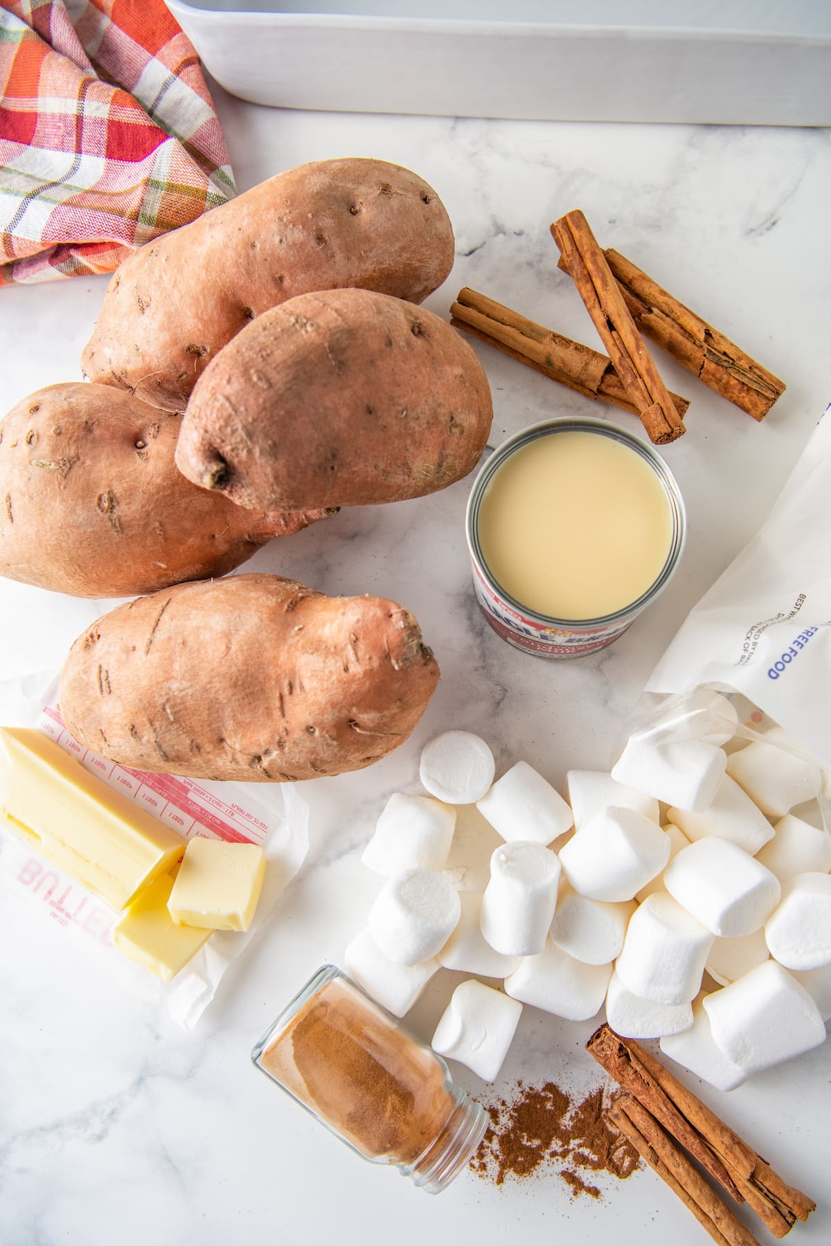 ingredients to make sweet potato casserole like sweet potatoes, condensed milk, butter, cinnamon, and marshmallow,
