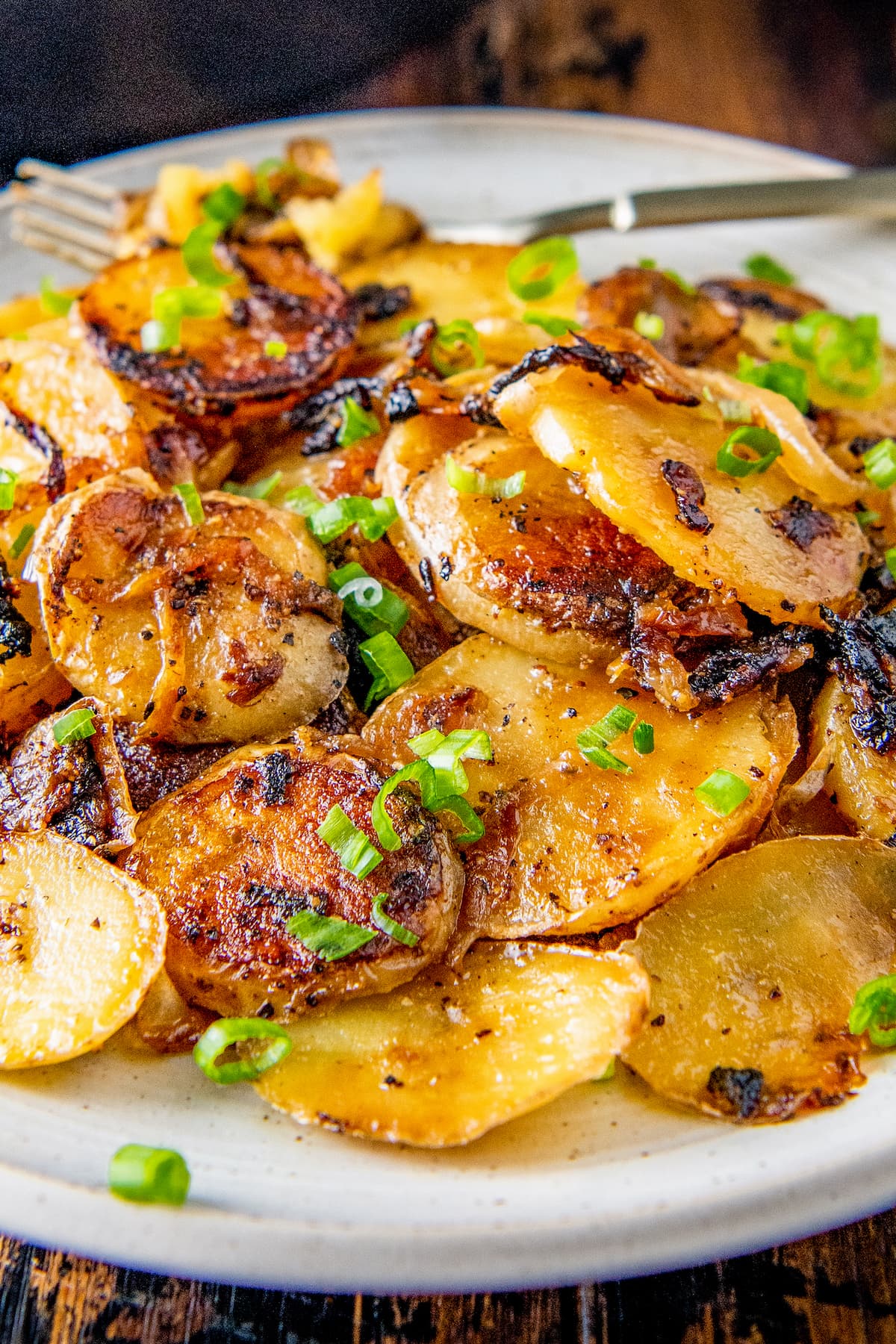 a plate of fried sliced potatoes and onions garnished with chives