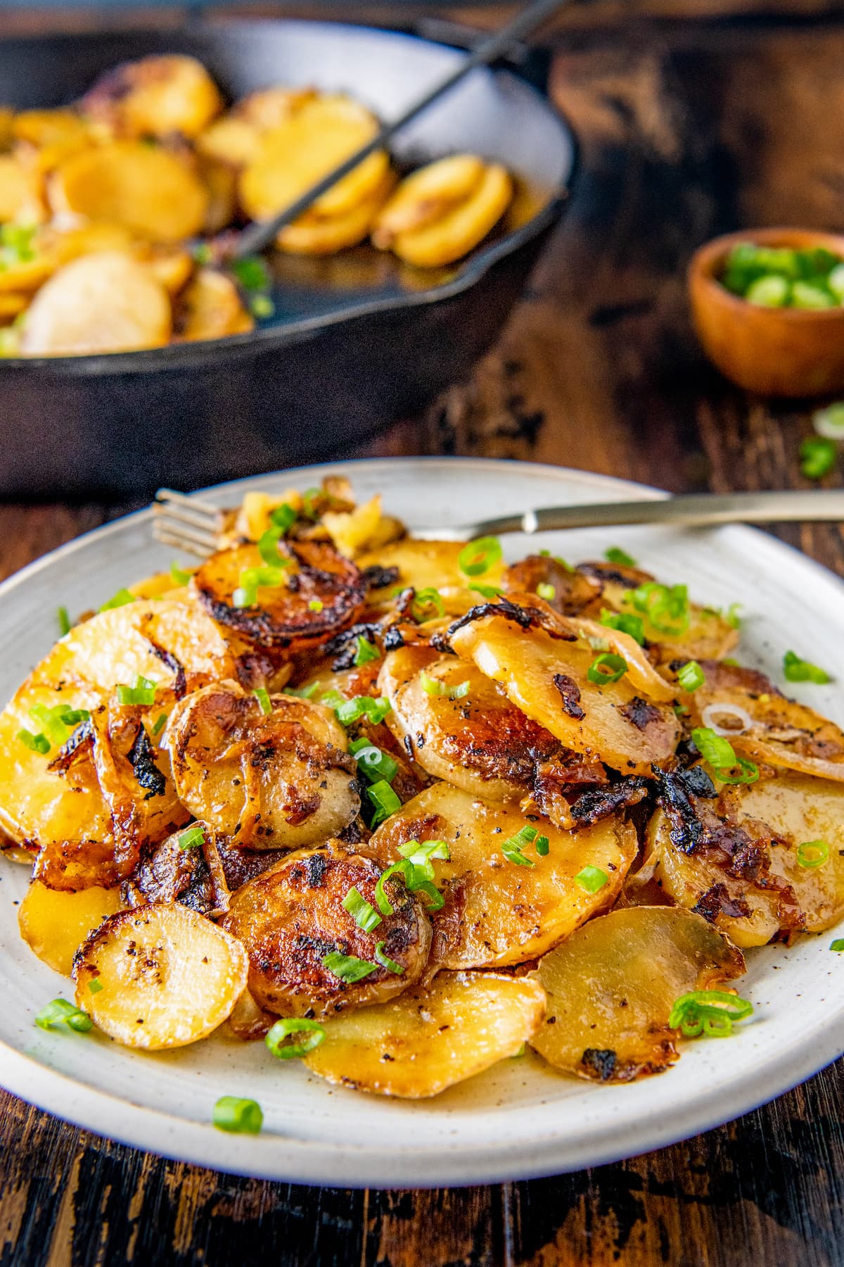 a plate of fried sliced potatoes and onions garnished with chives