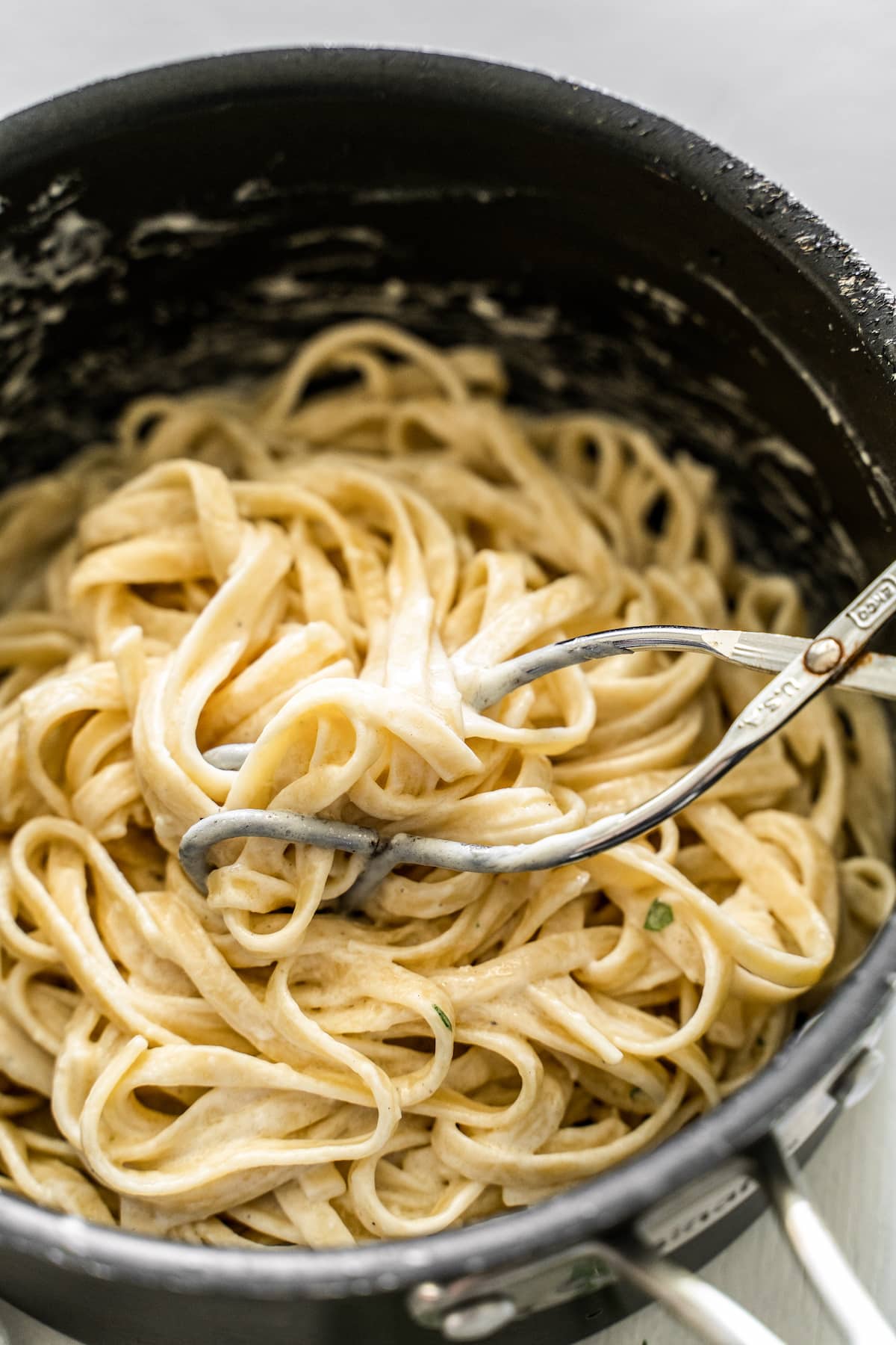 tongs mixing pasta alfredo
