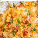 King ranch chicken casserole on a plate with rice and cilantro on top.