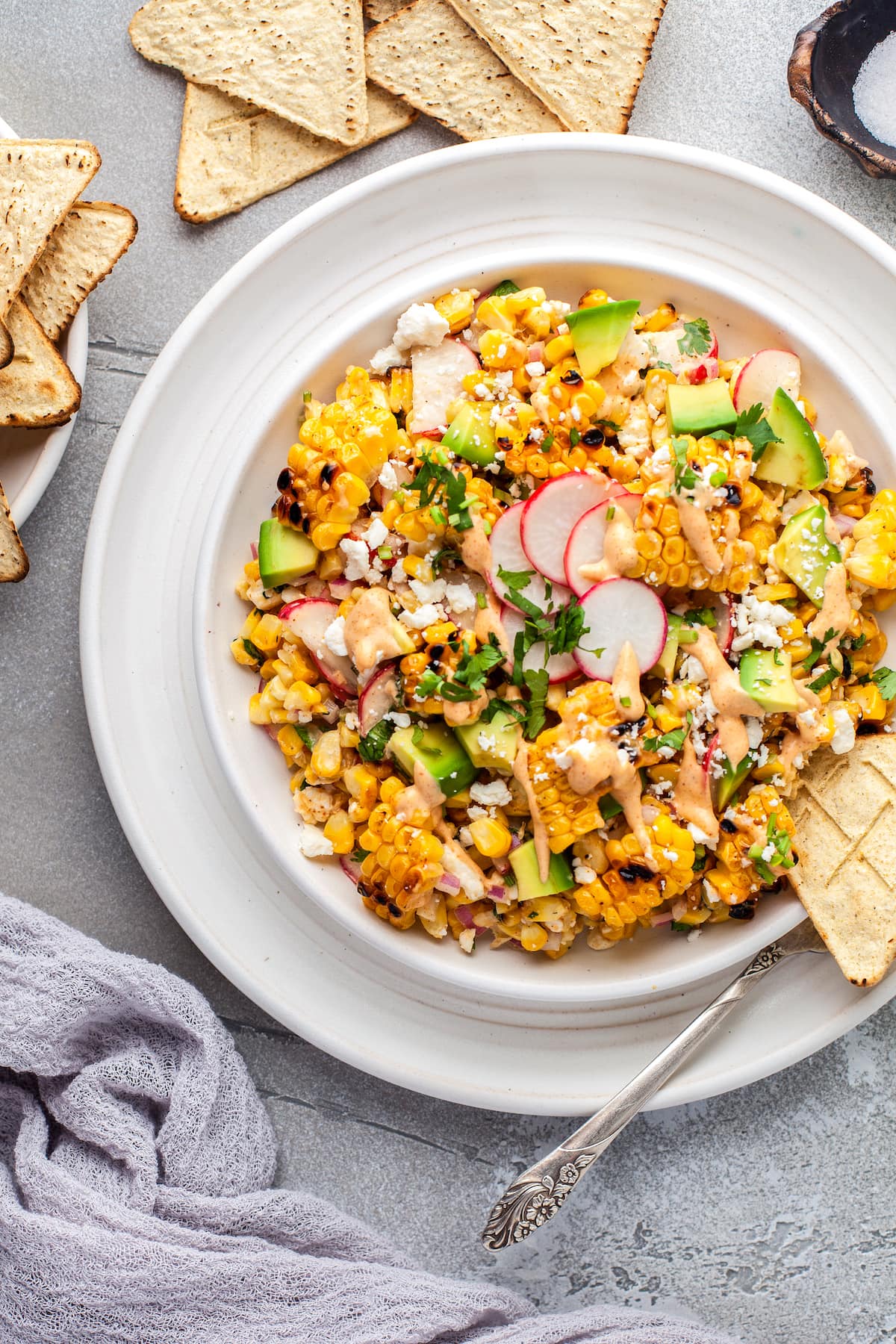 a large plate with Mexican Corn Salad that has corn, radishes, herbs, cheese, and creamy dressing