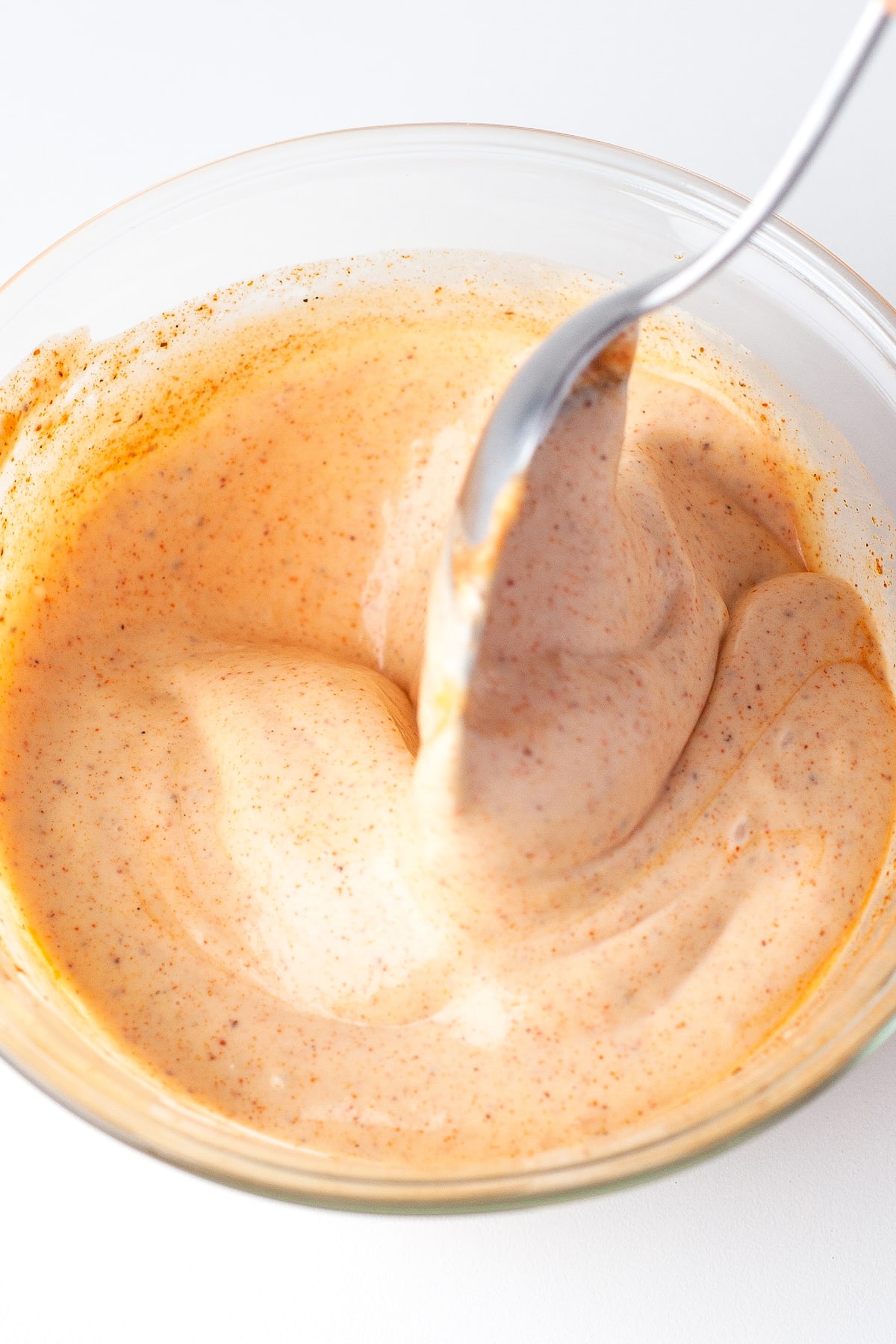 a spoon mixing a light red creamy chipotle dressing