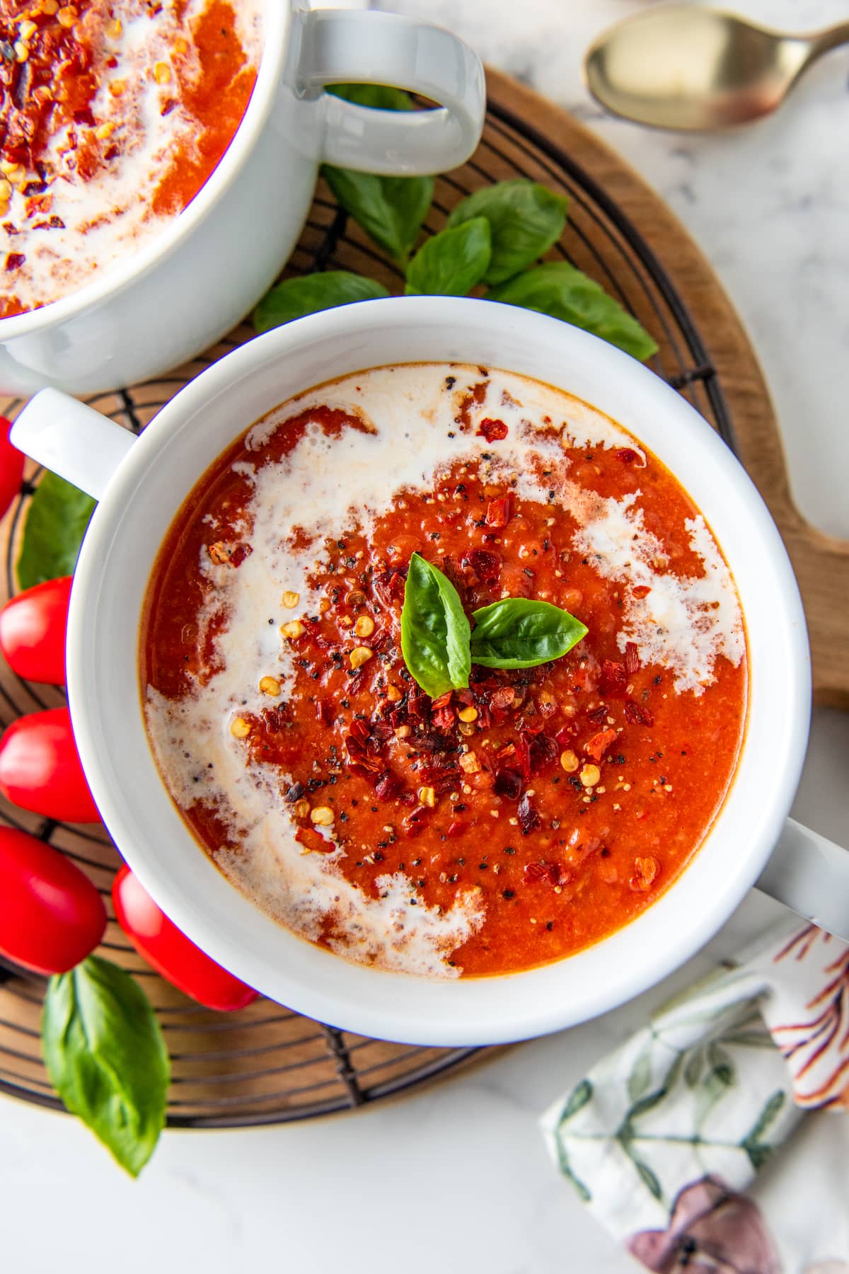a bowl of roasted tomato soup garnished with cream and basil