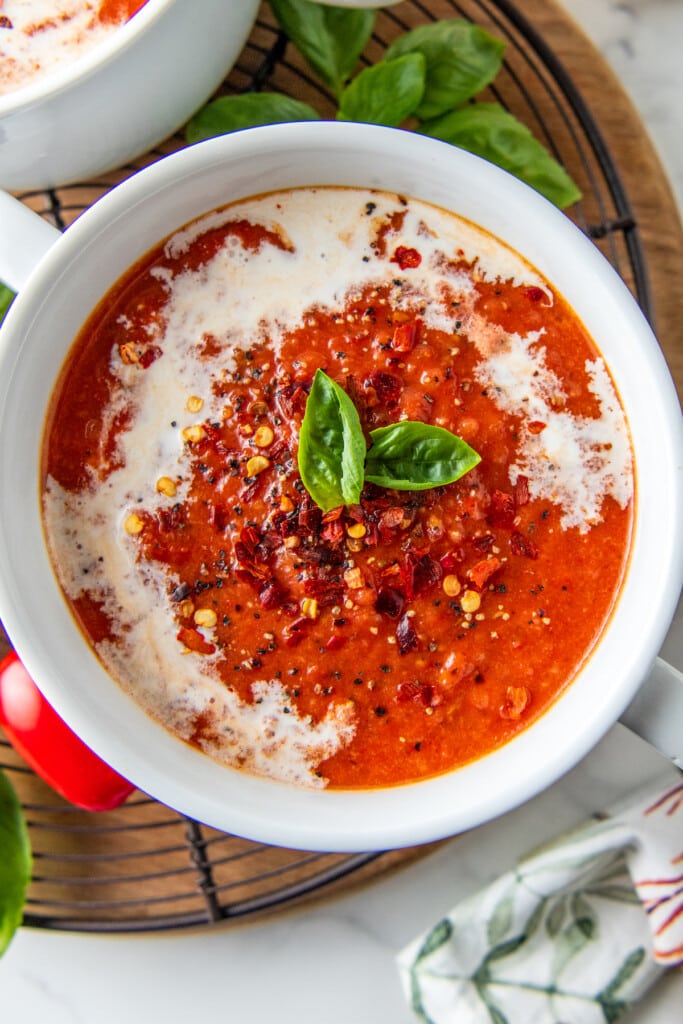 a bowl of roasted tomato soup garnished with cream and basil