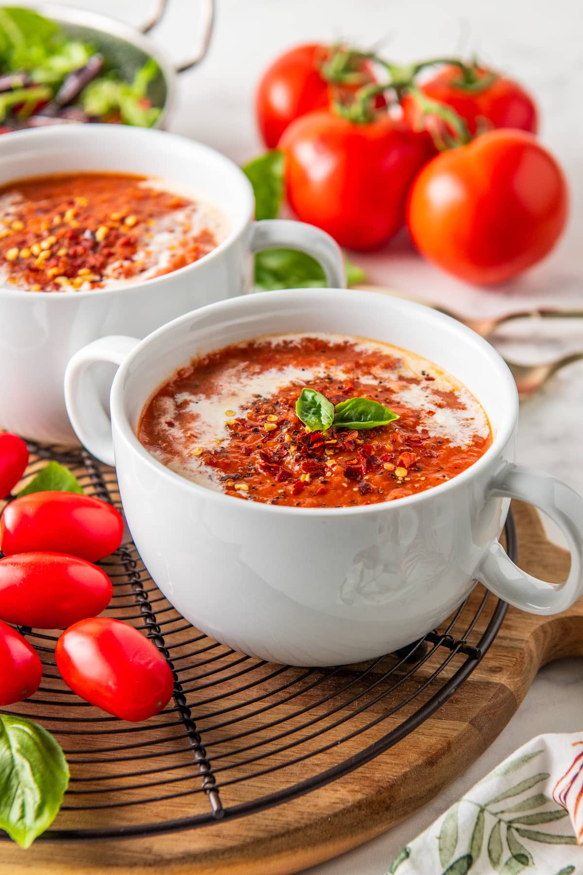 a bowl of tomato soup garnished with cream and basil