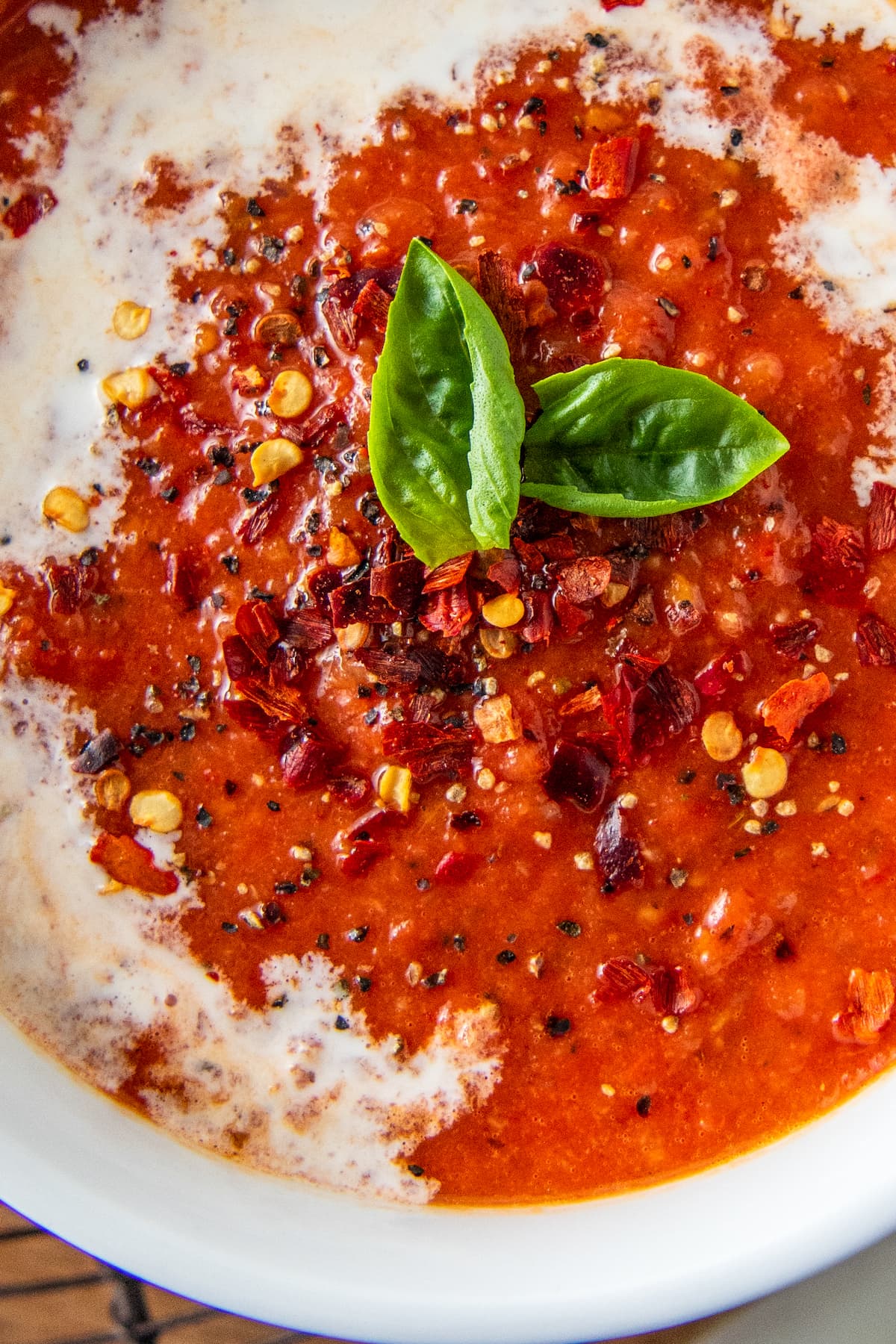 a bowl of tomato soup garnished with cream and basil