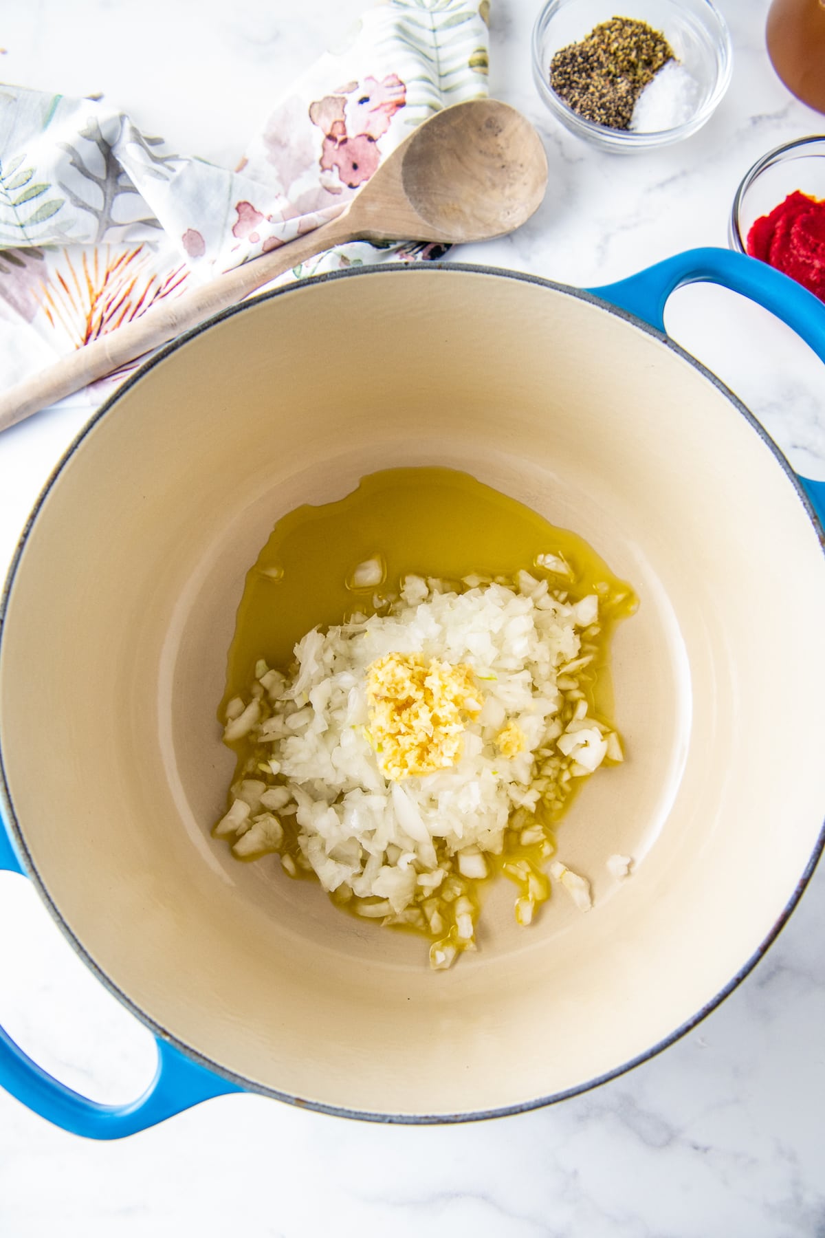 a large dutch oven with diced onions and garlic with olive oil