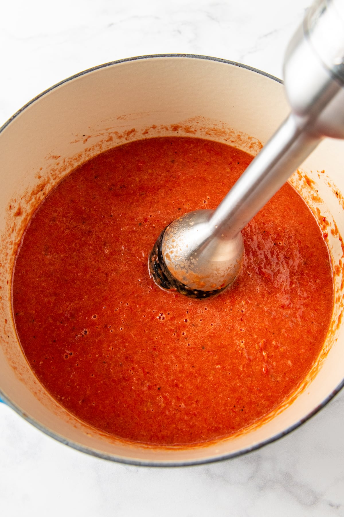 a large pot with an immersion blender pureeing roasted tomato soup